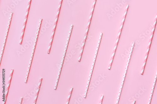 Pattern of pastel paper straws with white stripes and dots on soft pink background. Festive zero waste concept. Flat lay style.