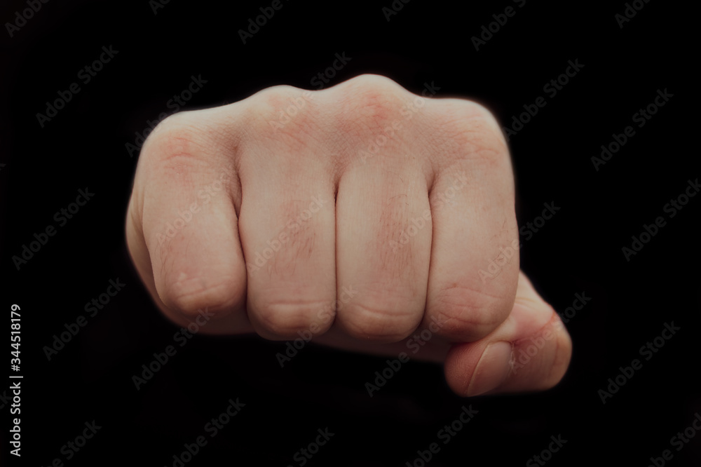 Hand clenched a fist on a black background. male punch close up Hand clenched a fist on a black background. male punch close up