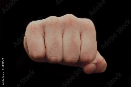 Hand clenched a fist on a black background. male punch close up