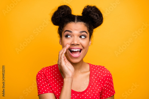Energetic positive afro american girl want share private information gossip with friend place hand lips whisper look copyspace wear red dotted t-shirt isolated bright shine color background © deagreez