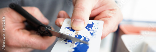 Fotografie Male hand cutting banking card with scissors