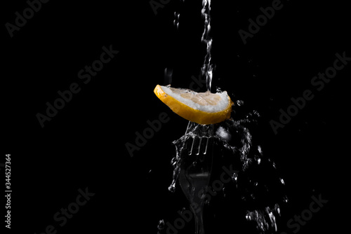 Fresh lemon on a fork. splashing water on bright sour lemon