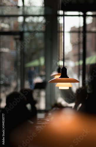 Ambience image of a lunchroom with the focus on the pendant lights, people are visible in the background as a silhouette. photo