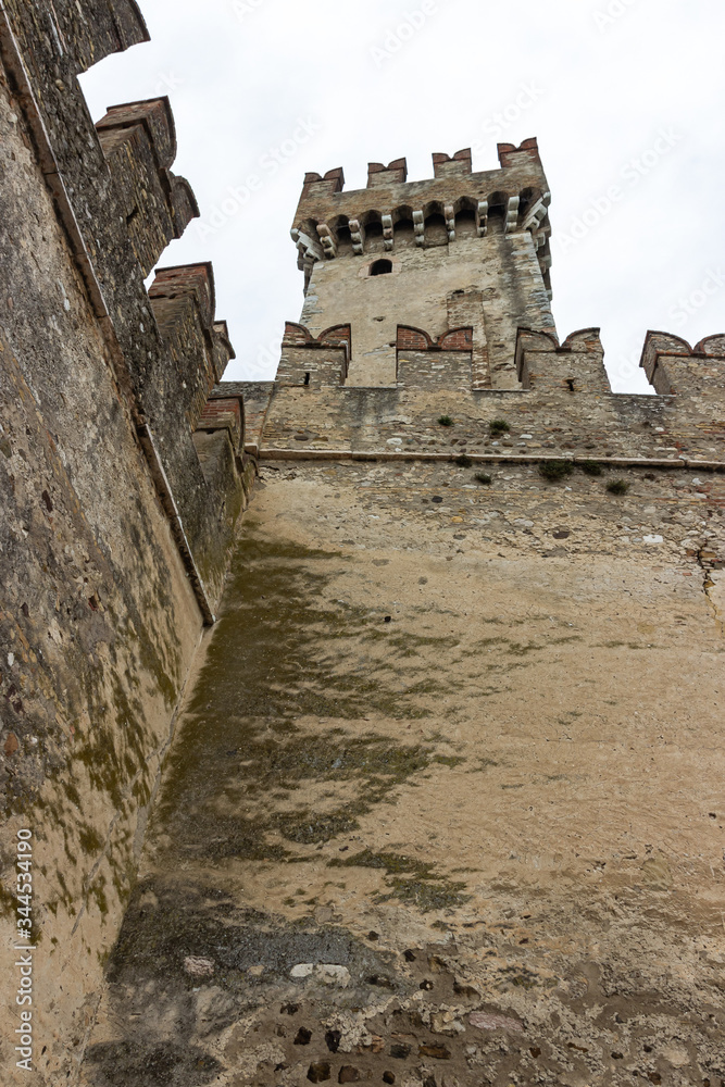 View of the corner tower of the Castello Scaligero fortress from the inner square in the Sirmione town in Lombardy, northern Italy