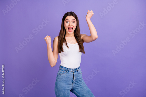 Photo of pretty attractive lady open mouth raise fists listen amazing news celebrating victory wear white singlet blue jeans isolated pastel purple color background