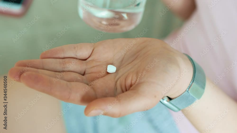 Young woman taking a pill from the temperature, sitting in the house on the couch, feeling sick with the virus, temperature symptom health couch blanket infection pills medicine Young woman taking a pill from the temperature, sitting in the house on the couch, feeling sick with the virus, temperature symptom health couch blanket infection pills medicine