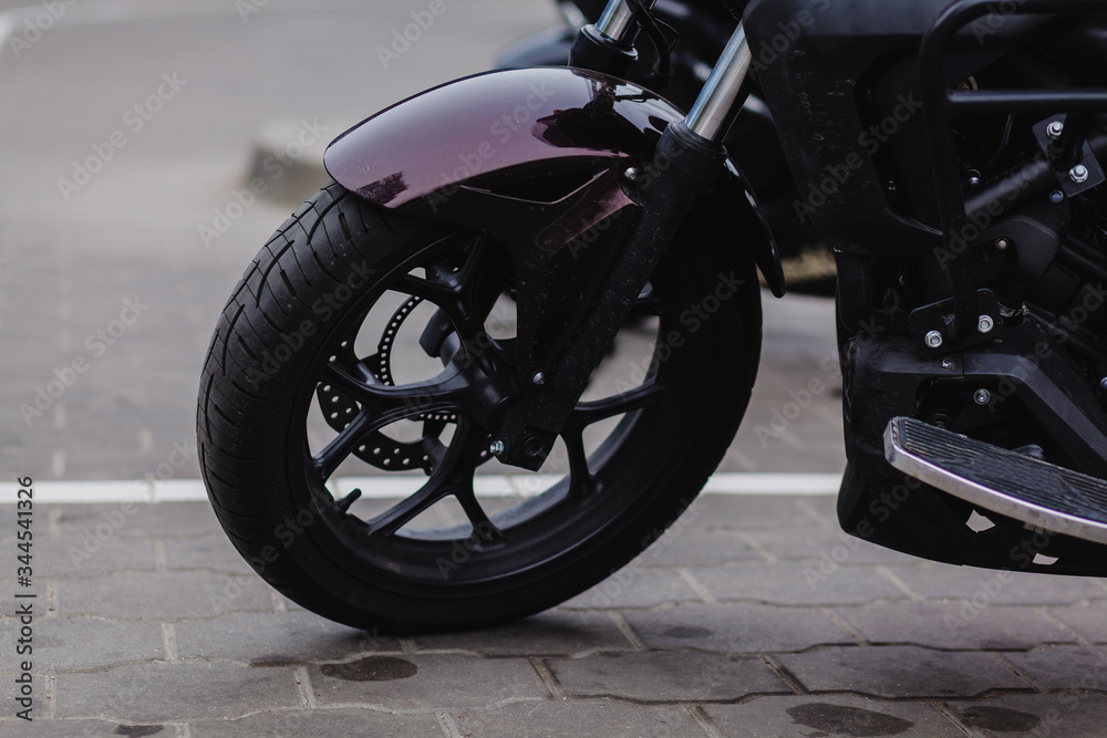 black wheel of a sports motorcycle standing on the asphalt.