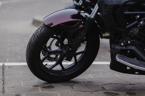 black wheel of a sports motorcycle standing on the asphalt.