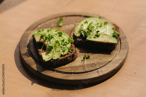 Avocado toast on wooden boadr. Vegetarian food concept. Fresh food at home. Sandwich with avocado and rye toasted bread, sesame seeds and mustard seedings