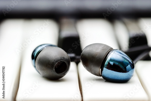 Stylish black headphones lie on the keys of the synthesizer.