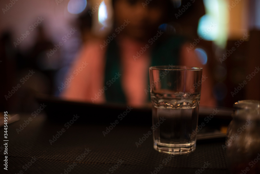 Glass half filled with drinking water on the table of a restaurant. Indian cafe