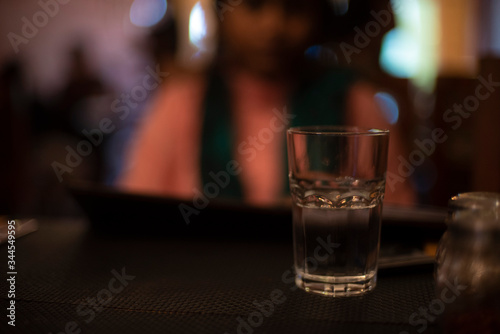 Glass half filled with drinking water on the table of a restaurant. Indian cafe