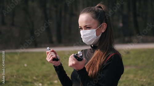 A sporty woman is doing her morning routine. She is going sport outside. The athletic woman is doing exercises with handgrips on a mat near the lake. photo