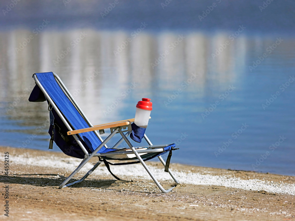 Chair on a sandy beach overlooking clear blue water Coronavirus isolation concept. Chair on a sandy beach overlooking clear blue water Coronavirus isolation concept.