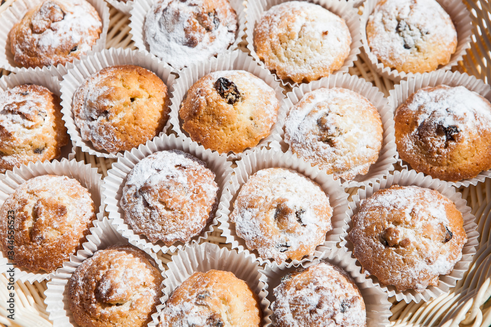 Top view of fresh baked muffins in paper cups. Set of cupcakes sprinkled with powdered sugar. Top view of fresh baked muffins in paper cups. Set of cupcakes sprinkled with powdered sugar.