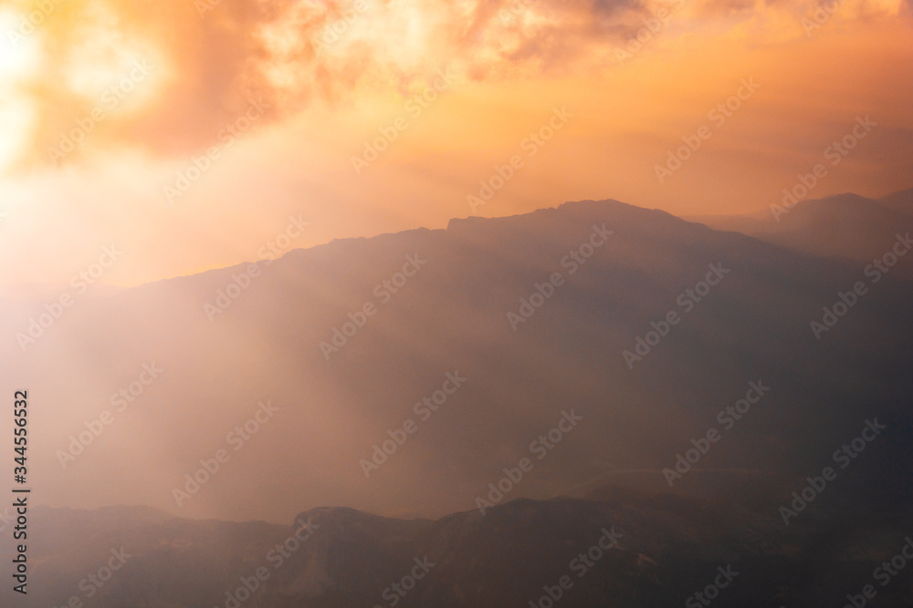 Sunrise above misty mountains from airplane window. Natural background.