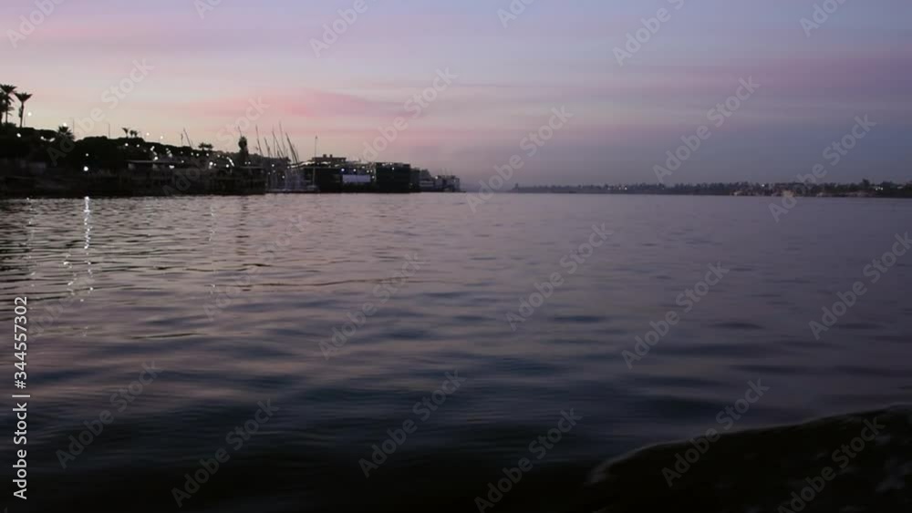 Nile river seen from boat passing by. Sunrise sky reflected on still water. Slow motion. Luxor, Egypt. Nile river seen from boat passing by. Sunrise sky reflected on still water. Slow motion. Luxor, Egypt.