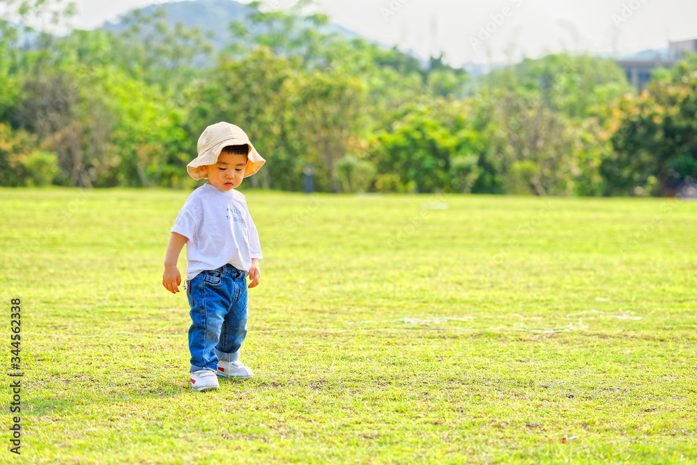 The little boy in a hat in the outdoor lawn
