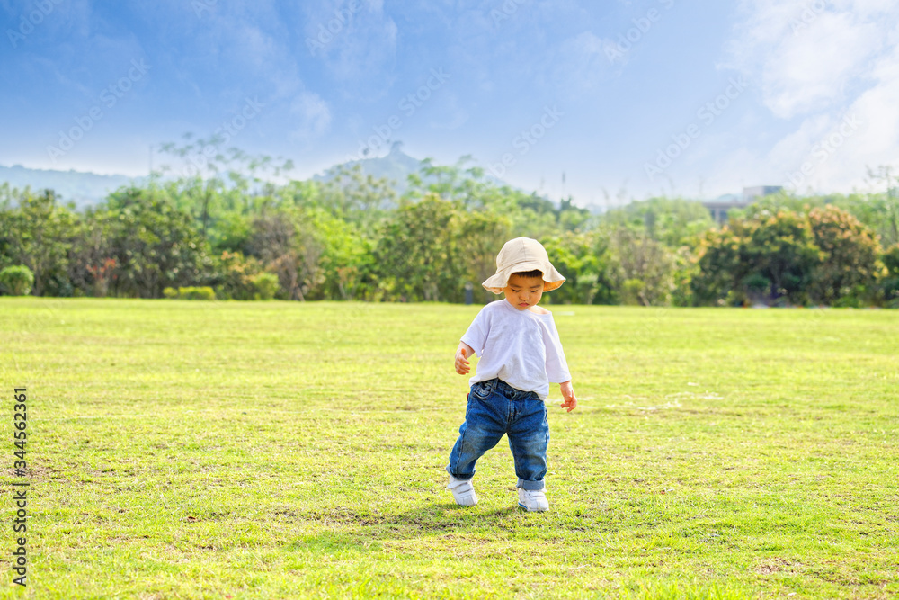 The little boy in a hat in the outdoor lawn
