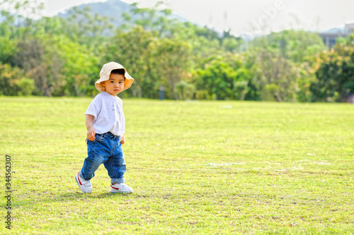 The little boy in a hat in the outdoor lawn 