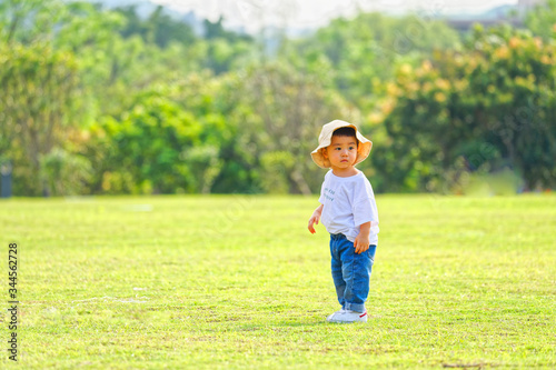 The little boy in a hat in the outdoor lawn 