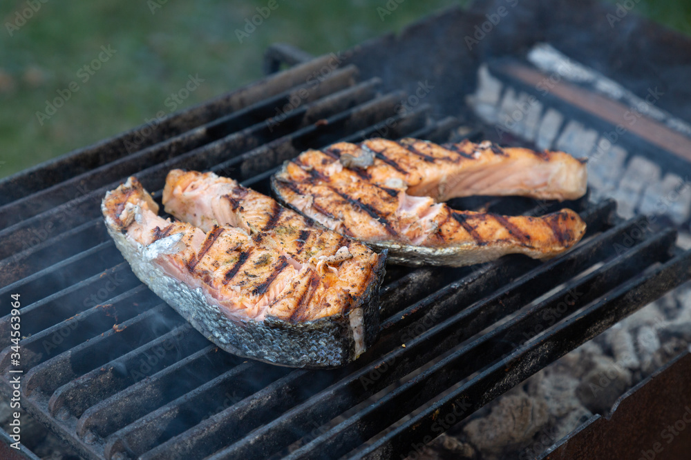 two large pieces of grilled salmon steak lie on a barbecue grill outdoor two large pieces of grilled salmon steak lie on a barbecue grill outdoor
