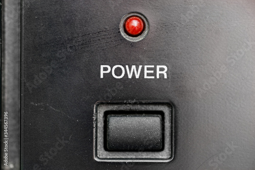 An old, dusty, scratched power button with a red led light.
