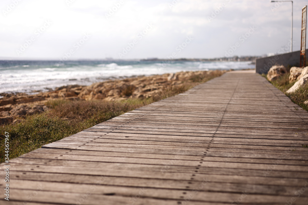 Beautiful wooden pedestrian walkway along the seashore. Footpath is paved with vintage boards. Natural wood planks on the beach background.