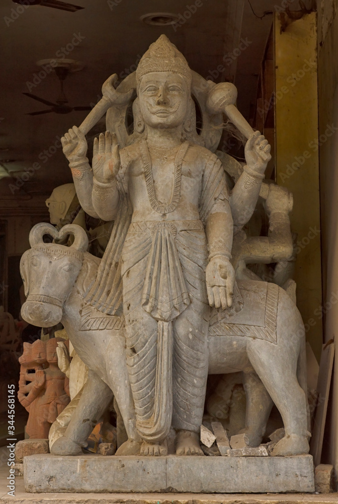 A carved stone statue of a Hindu God standing in the entrance of a shop in Delhi