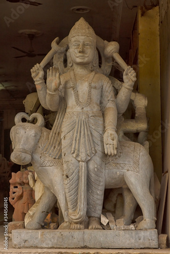 A carved stone statue of a Hindu God standing in the entrance of a shop in Delhi