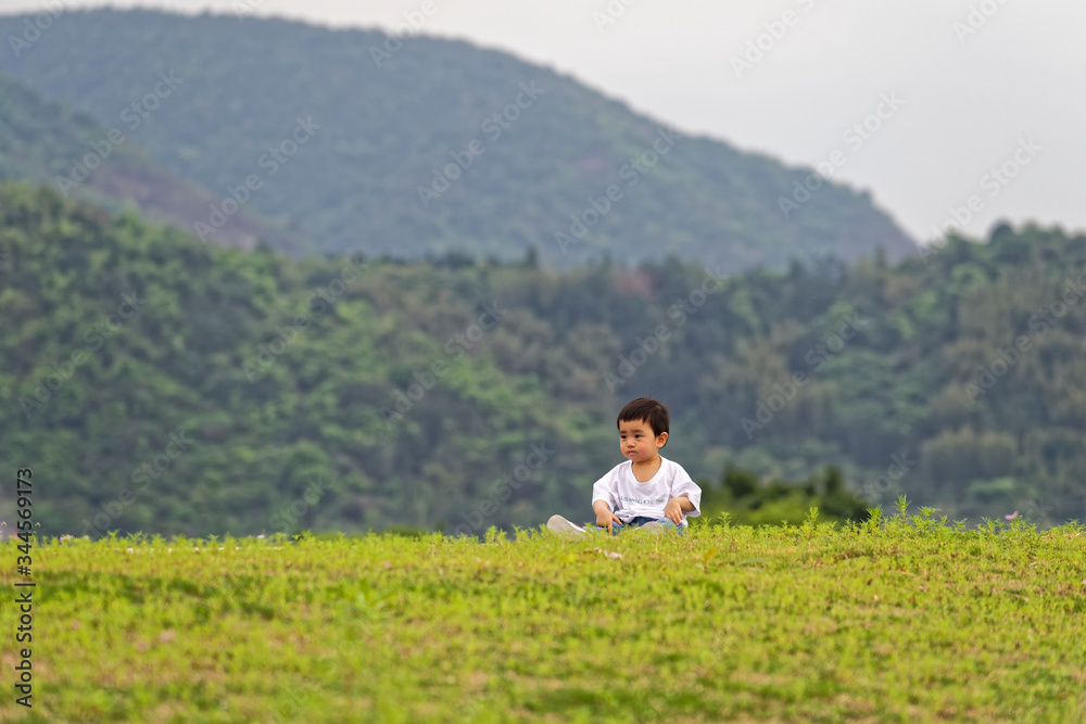 A little boy sitting on the grass