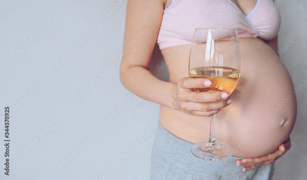 Isolated portrait of unrecognizable pregnant woman holding glass of wine and showing her big belly. Pregnancy, motherhood, unborn and expectation. Bad habits concept. Free space for text mockup Isolated portrait of unrecognizable pregnant woman holding glass of wine and showing her big belly. Pregnancy, motherhood, unborn and expectation. Bad habits concept. Free space for text mockup