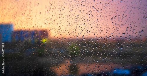 Raindrops on the window. Sunset, evening time in the city.