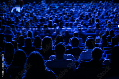 The audience in the cinema  the view from the back. Group of people at the business conference  back view  blue tones