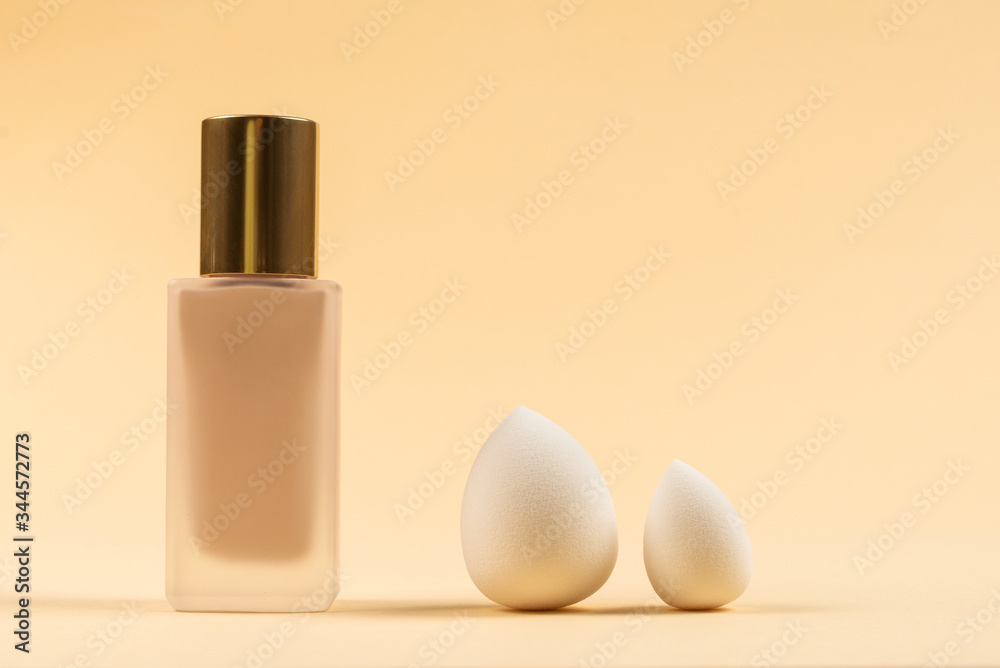 Small, medium and large white beauty blender and makeup foundation on beige background. Small, medium and large white beauty blender and makeup foundation on beige background.