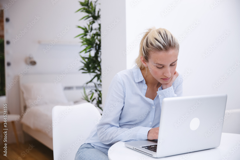 Young blonde woman working with computer at home. Young blonde woman working with computer at home.