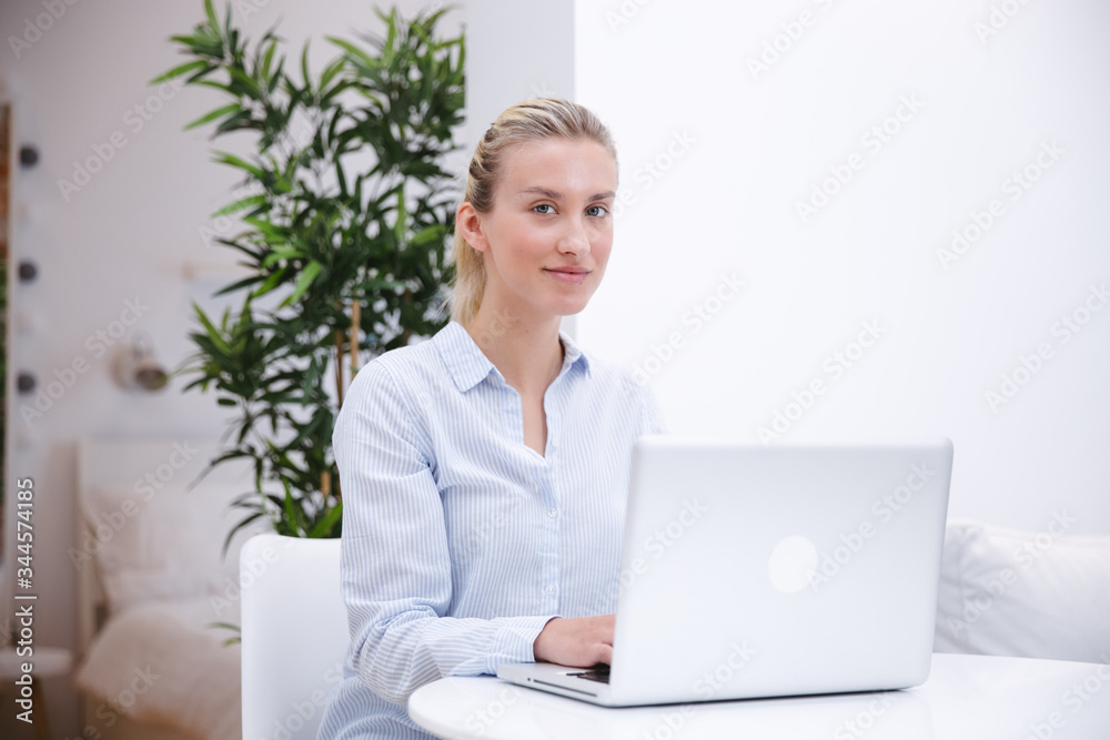 Young blonde woman working with computer at home. Young blonde woman working with computer at home.