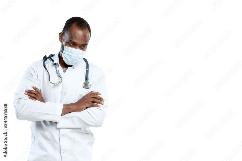 Hands crossed. Male young doctor with stethoscope and face mask on white studio background. Looks sad, serious. Concept of healthcare and medicine, coronavirus pandemic, danger epidemic, COVID. Hands crossed. Male young doctor with stethoscope and face mask on white studio background. Looks sad, serious. Concept of healthcare and medicine, coronavirus pandemic, danger epidemic, COVID.