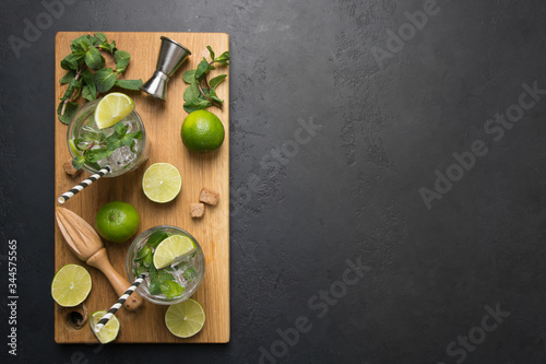 Mojito cocktail ingredients, lime, mint, water, jigger on black table. View from above. Horizontal format.