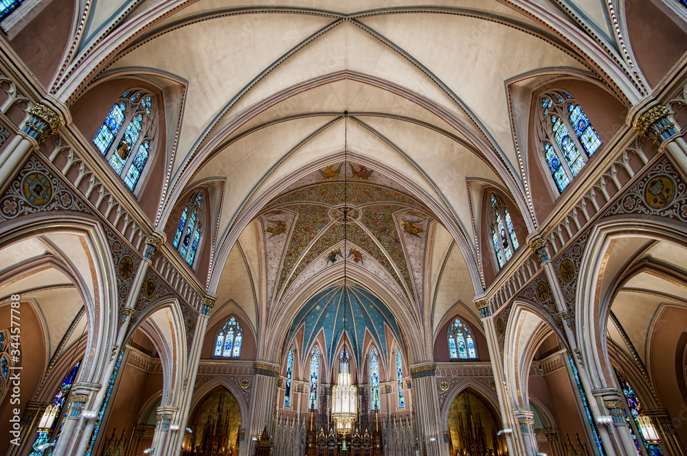 Wide angle view of catholic church catherdral front and ornate painted ceiling  with multiple arches and stained glass windows