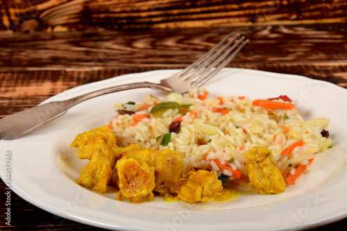 colorful rice with vegetables and pieces of chicken in a curry spice