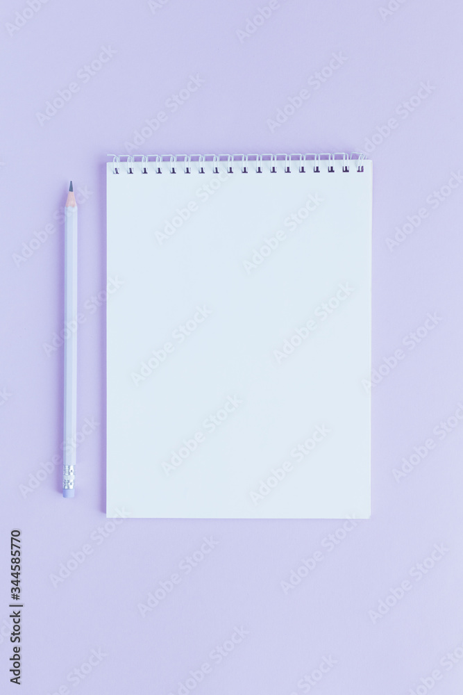 Notebook with blank page and pencil on a violet background.