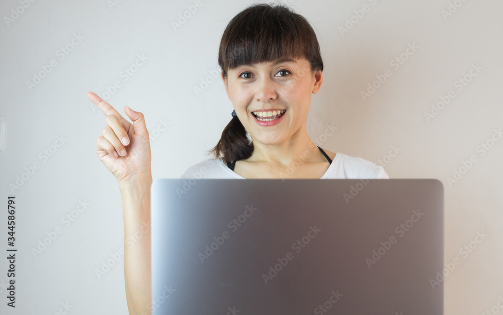 Young asian woman smiling and pointing finger with loptop. Young asian woman smiling and pointing finger with loptop.