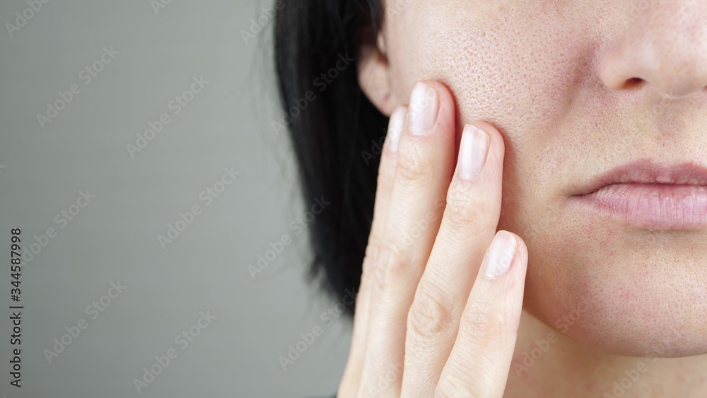 The woman touches the skin on her face. Problem skin with enlarged pores. Part of a woman's face. Beauty and health The woman touches the skin on her face. Problem skin with enlarged pores. Part of a woman's face. Beauty and health