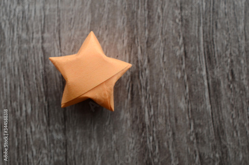 A lucky orange origami star on wooden