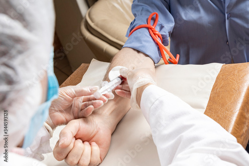 Doctor takes blood from a vein for analysis by a patient. The nurse takes a blood test. Side view. Closeup.