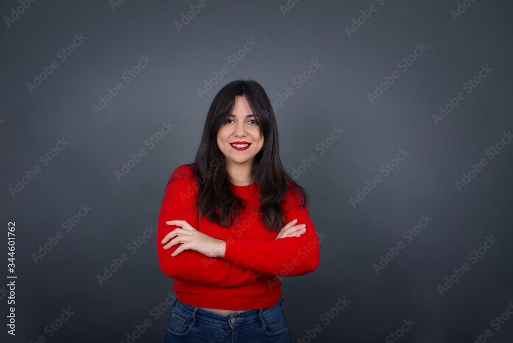 Obraz premium Brunette girl happy face smiling with crossed arms looking confident at the camera standing against gray wall. Positive person.