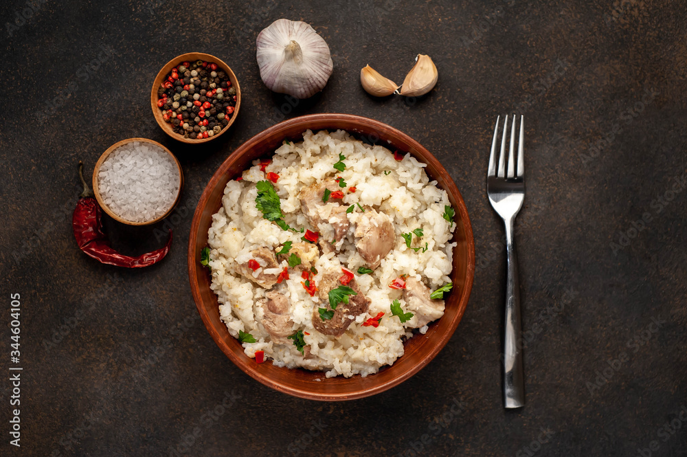 Homemade pilaf with meat and spices in a bowl on a stone table. Eastern cuisine. Homemade pilaf with meat and spices in a bowl on a stone table. Eastern cuisine.