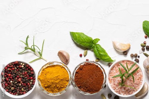 Assortment of spices and herbs on white concrete background with copy space for your text.