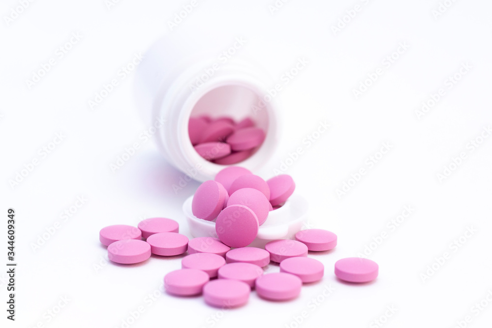 pills of pink color from a white jar on a white background. The concept of health care, treatment, illness. pills of pink color from a white jar on a white background. The concept of health care, treatment, illness.